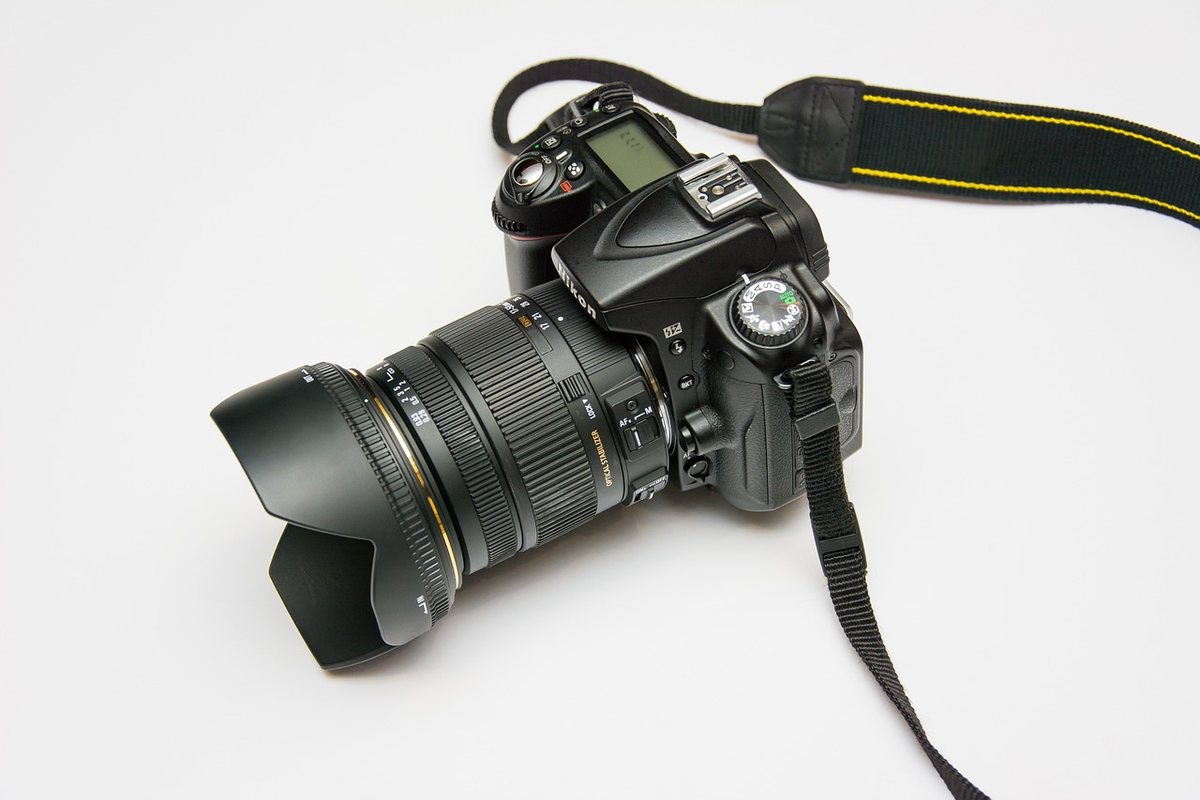 Appareil photo DSLR noir avec objectif et sangle sur fond blanc